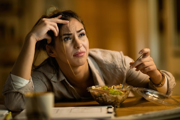 Tired woman resting head on arms at kitchen table with healthy food